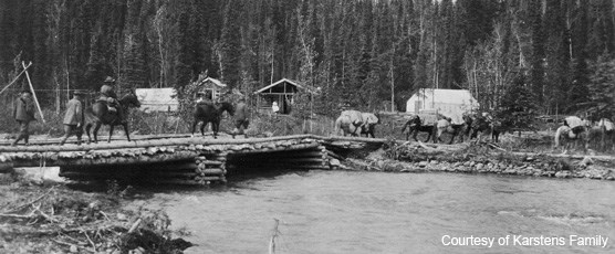 Riders on horseback crossing a creek via a wooden bridge Riders on horseback crossing a creek via a wooden bridge