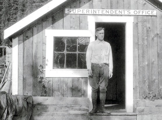 Historic image of a man standing outside a rustic building
