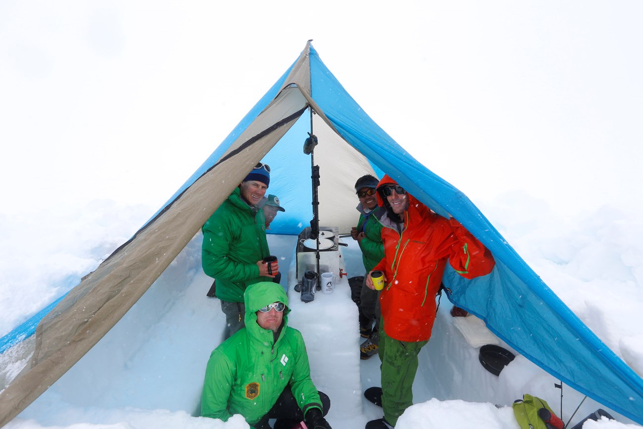 Climbers prepare a meal in a ventilated cook tent