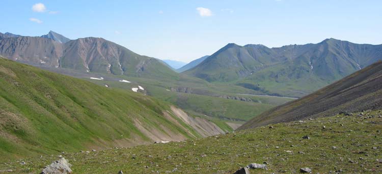 tree-less hills in front of tall mountains