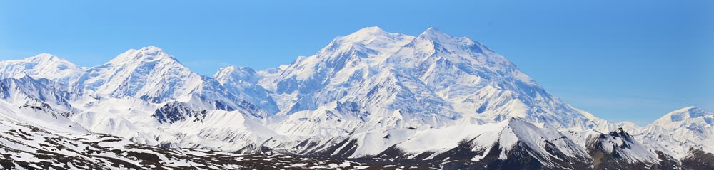 landscape of snowy mountains, with one mountain particularly huge in comparison to the ones around it
