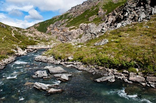 a shallow blue river flowing between two mountains