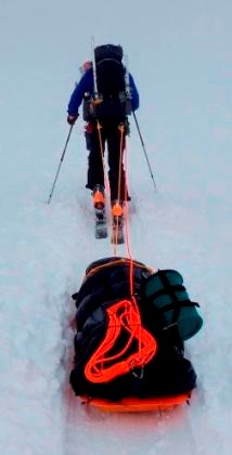 Climber towing heavy sled uphill