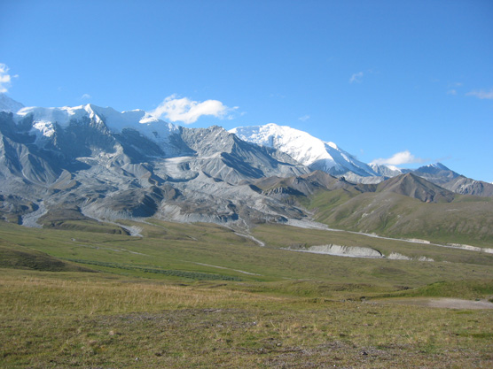 vast tree-less plain leading up to rugged mountains capped with snow