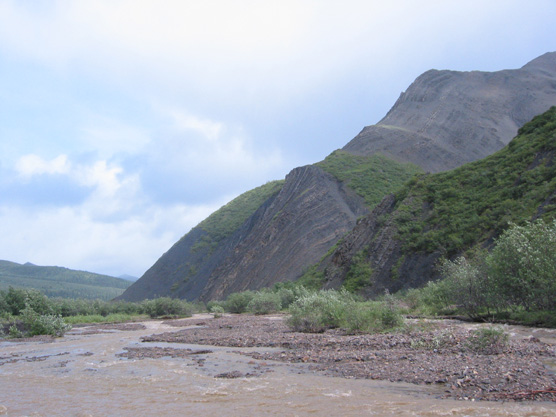 a river flowing past a steep hillside