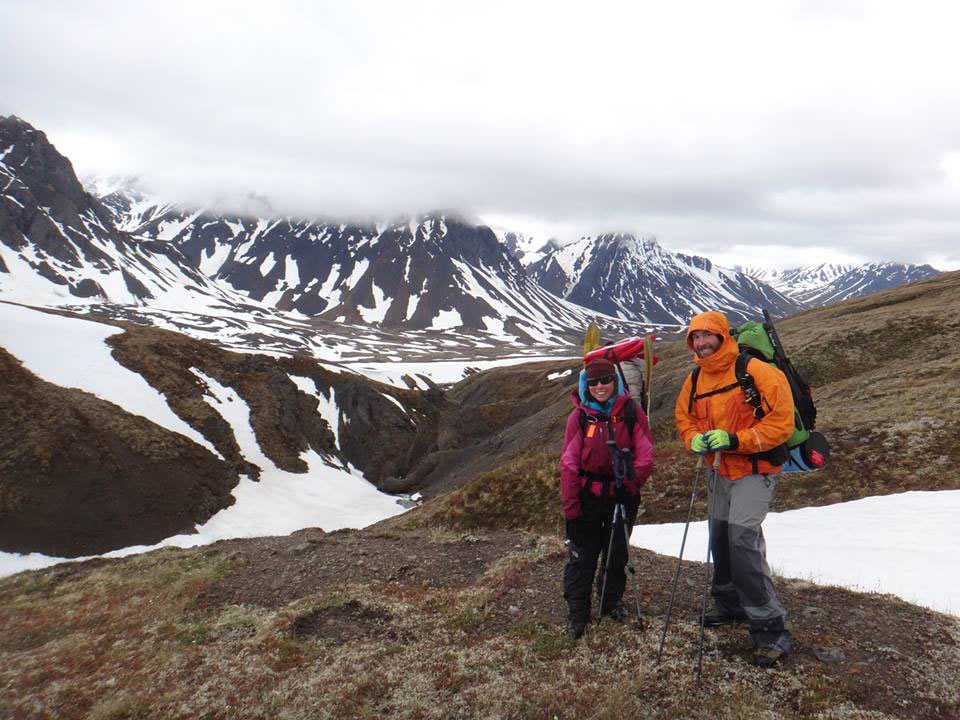 Two people with large packs hiking in snowy mountains