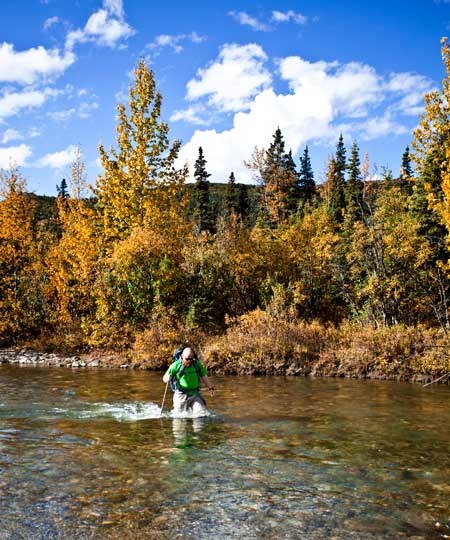 a man wades through a thigh deep river