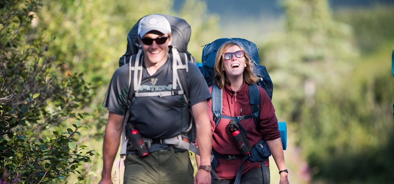 Bear spray can help keep you safe! two backpacker smile as they walk down a path
