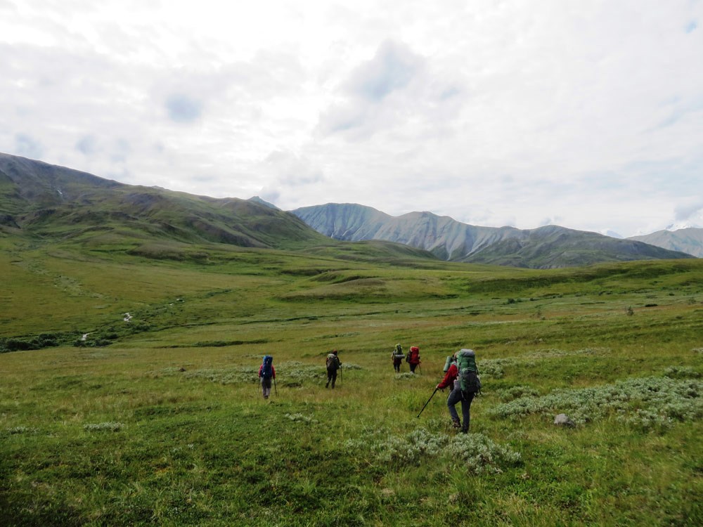 a group of people hiking through a tree-less landscape of hills and mountains