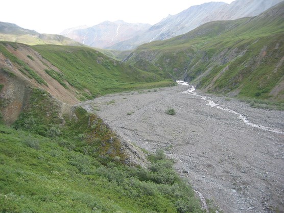 a river cutting a narrow, deep divide between two small ridges