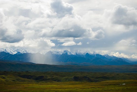 a cloudburst of rain over a small area in a landscape of mountains