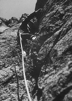 Black and white photo of a man rock climbing