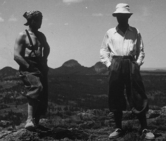 Two men standing with rounded hills in background