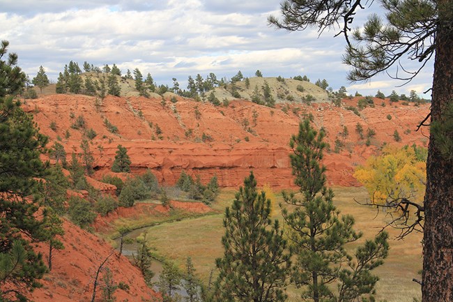 Red cliffs with a river and grassy field below