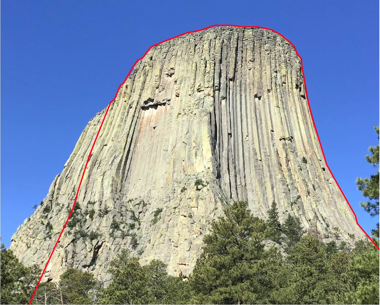 East and North East sections of devils tower outlined by a red line to say were the falcon climbing closure is.  Blue sunny day, pine trees in the foreground.