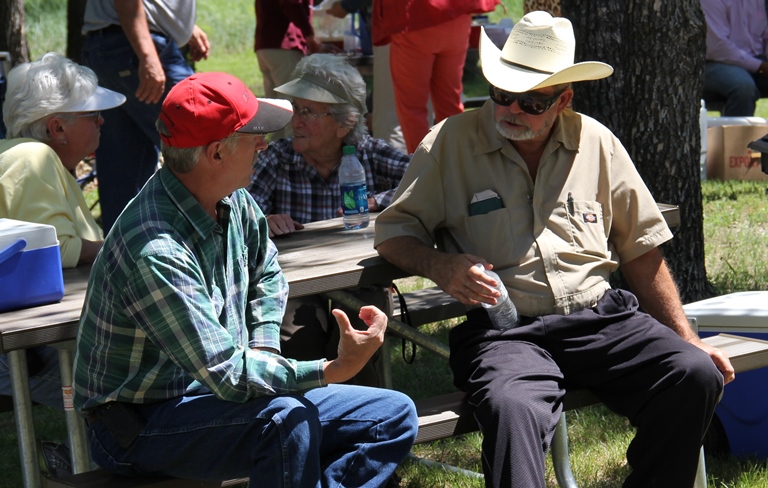 People sitting around a picnic table talking.