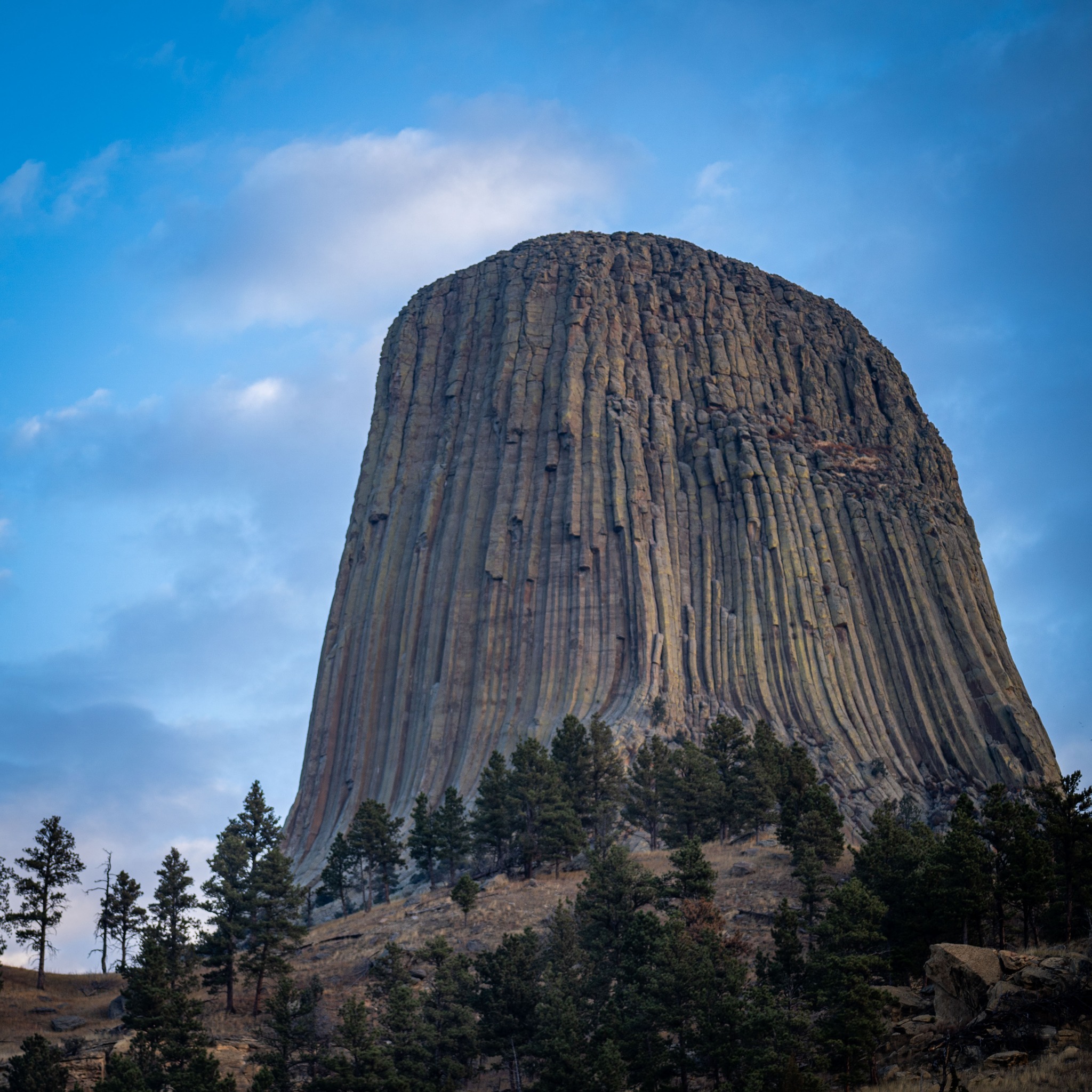 Bear Lodge or Devils tower rises out of the air on a partly cloudy day