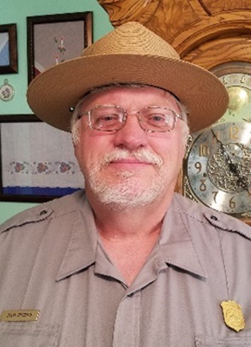 A ranger stands in uniform with a clock in the background