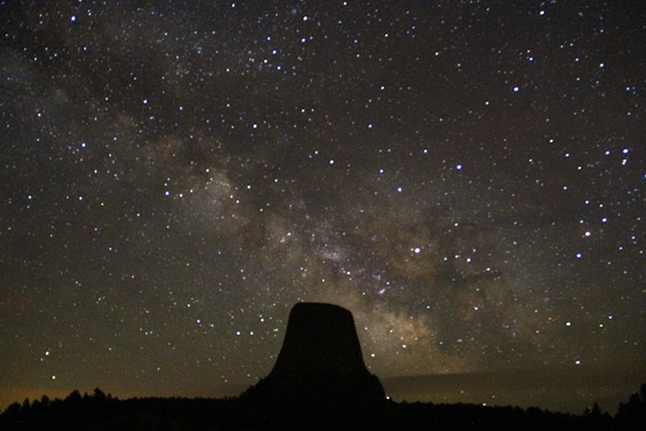 A night sky photo of Devils Tower with the Milky Way in the sky