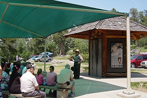 Many ranger programs take place in the center of the visitor center parking area. A park ranger addresses a group of visitors