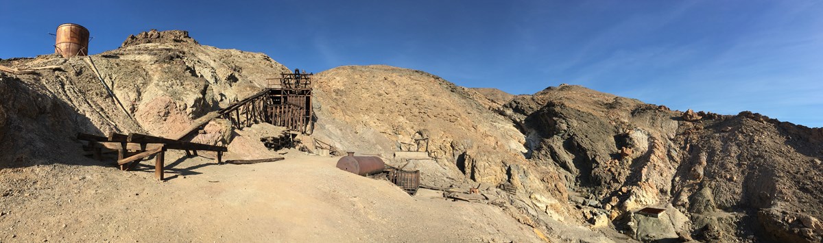 A panoramic image of old wooden structures set across a desert canyon.
