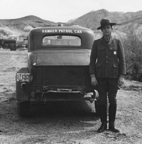 A black and white photo of a ranger in front of a vehicle which reads "Ranger Patrol Car"