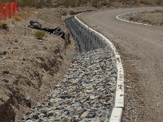 an unpaved road with gravel and boulders at the edge