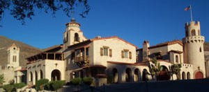 A massive two-story stucco building with red tile roof and a tower.