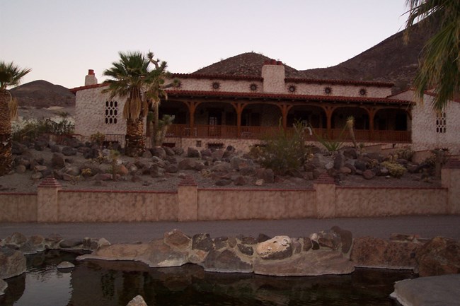 A two-story stucco-walled building with a red tile roof.