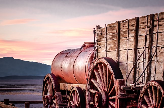 Historic wood and metal twenty mule team wagon in pink evening light.