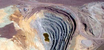 A large terraced mining hole dug into a multicolored desert.
