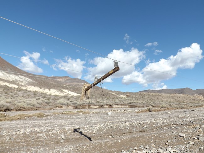 A wooden cross arm hangs from power lines with no pole beneath it.