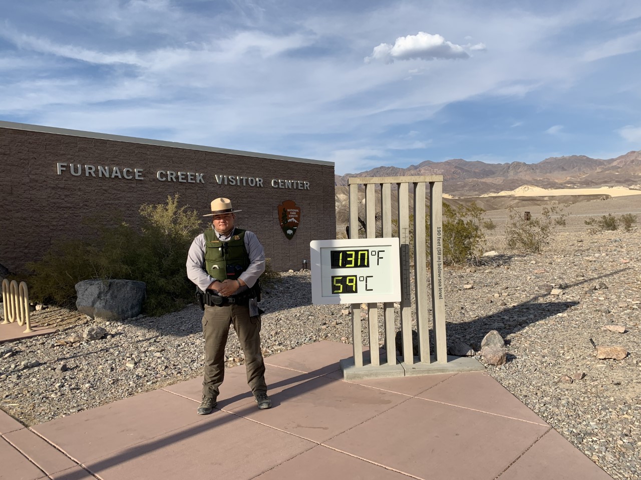 Park Ranger with thermometer at Furnace Creek Visitor Center A ranger stands next to a thermometer that reads 130F/59C.