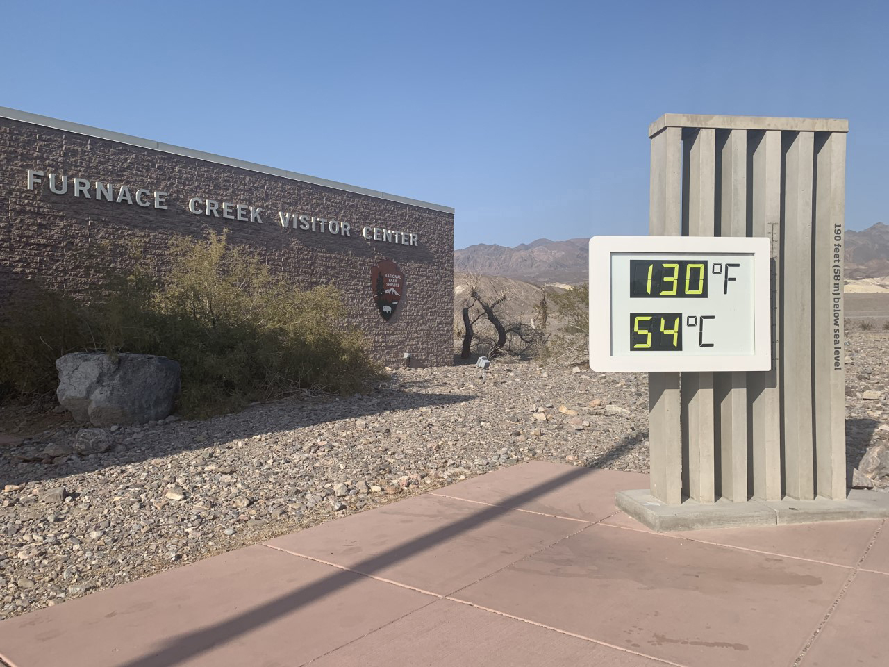 A display thermometer reads 130 F 54 C in front of a brick building.