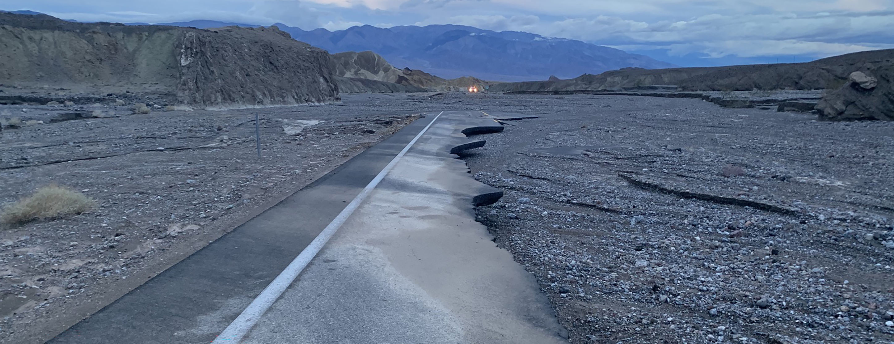 Damaged section of CA-190 with broken asphalt. Mountains frame the image.