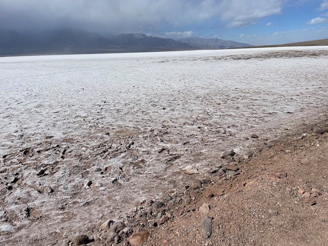 Brown mud and white salt flats extend to distant mountains.