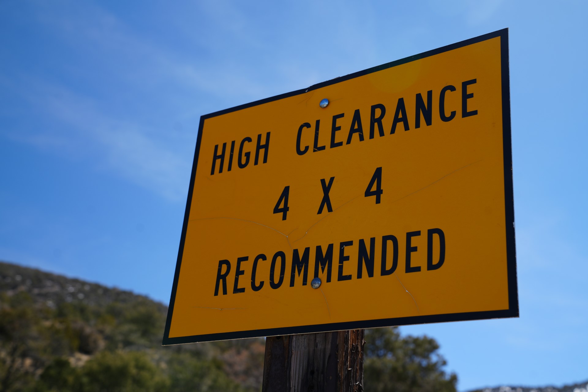 Yellow sign against blue sky that reads "High Clearance 4x4 Recommended"