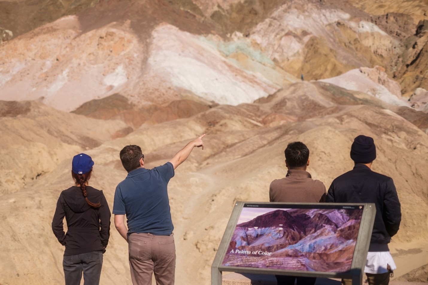 Visitors at Artists Palette people viewing colorful hills, with an informational sign