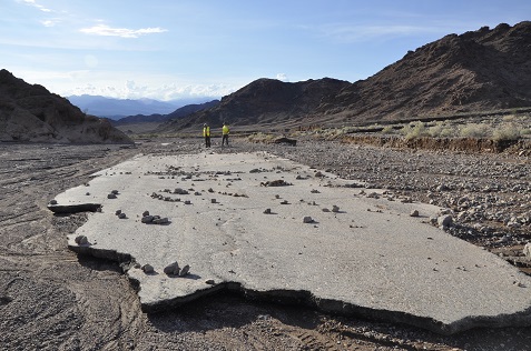 Two NPS employees walk on a damaged section of road after October's flood.