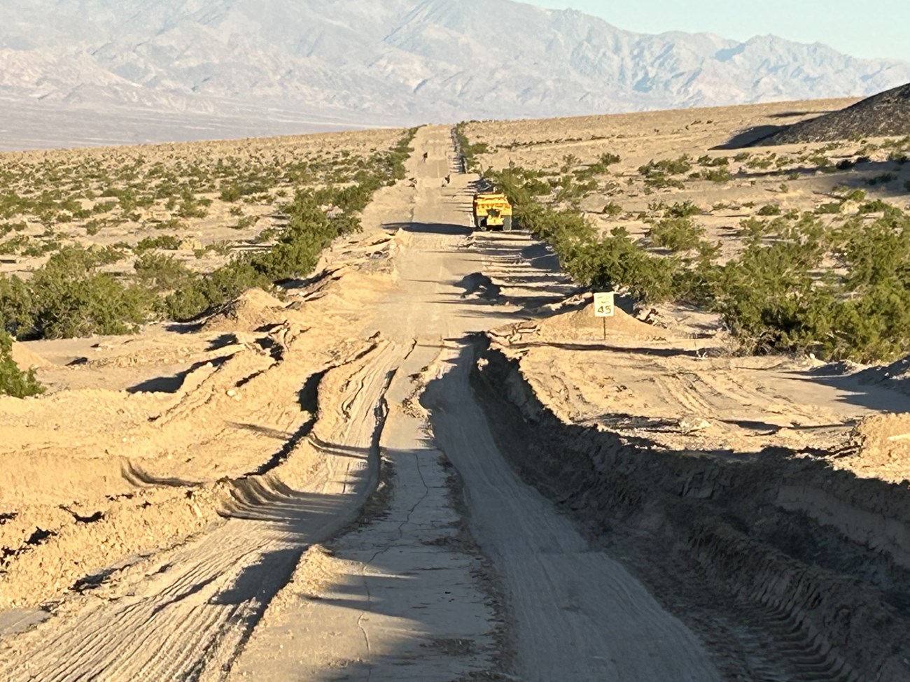 One lane plowed through brown dirt covering a desert road.