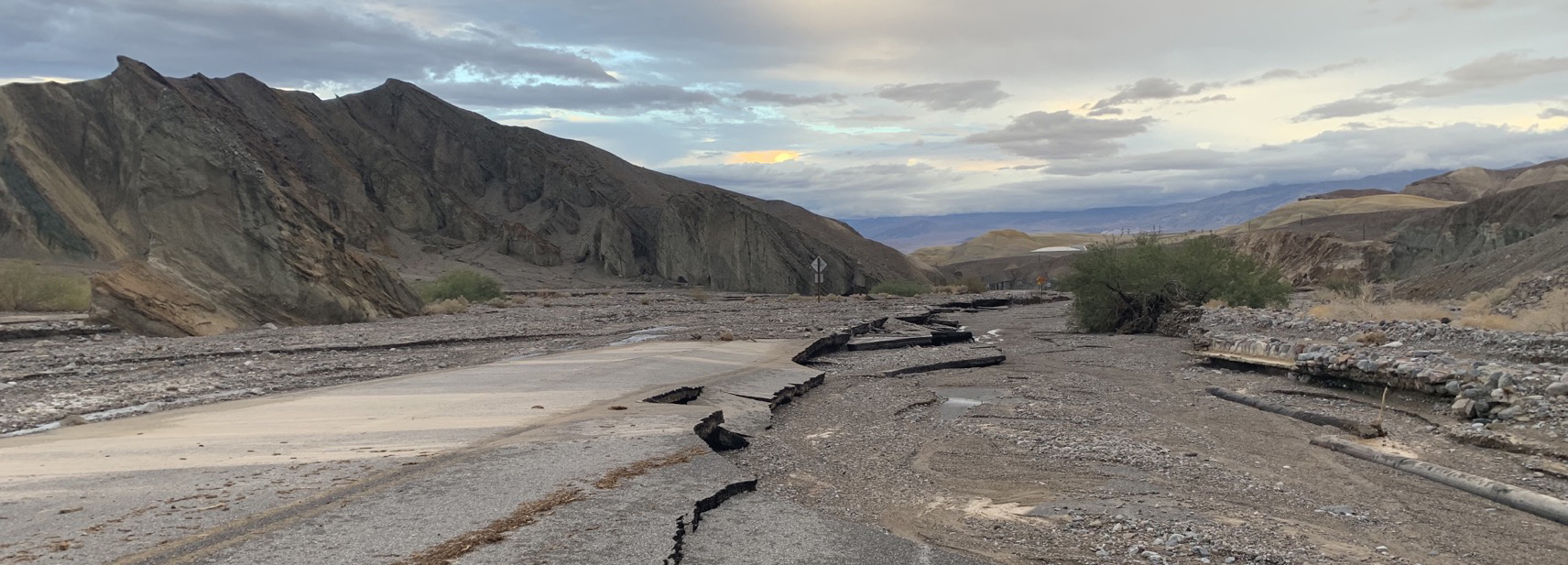 A mountain landscape outlines a stretch of road destroyed by flood waters.