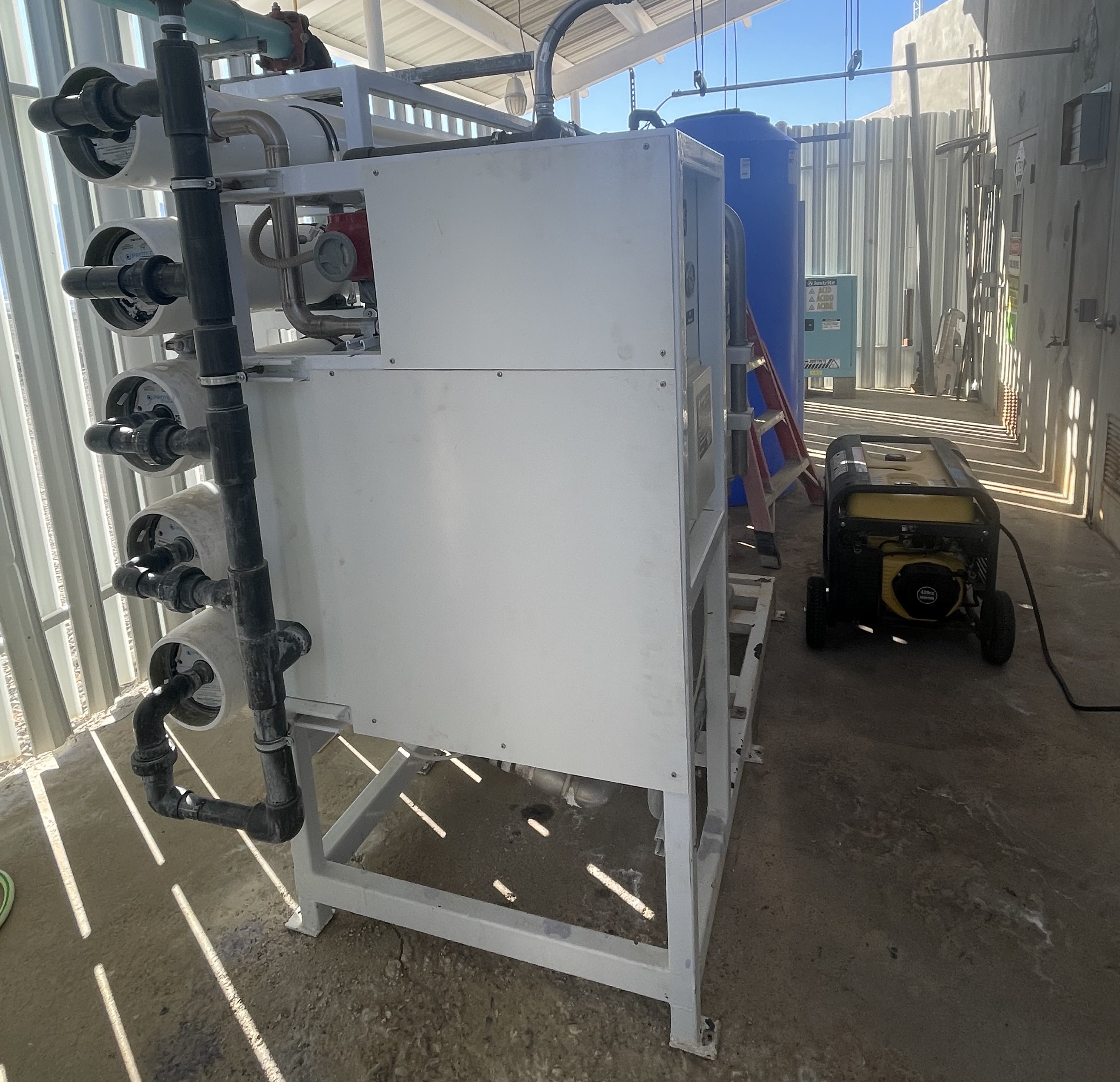 A yellow and black generator sits next to white-colored equipment that treats water.