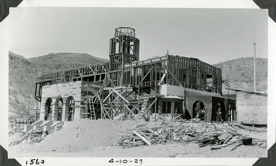 Black and white photo of a two-story building under construction, surrounded by scaffolding. "1560" and "4-10-27" are hand-written on the bottom.