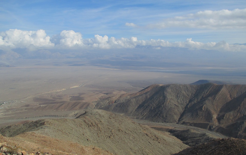This photo shows sweeping views of a parcel of land added to Death Valley NP. The photo shows hills and a wash in the foreground. In the background is nearby Panamint Springs Resort and Panamint Valley.