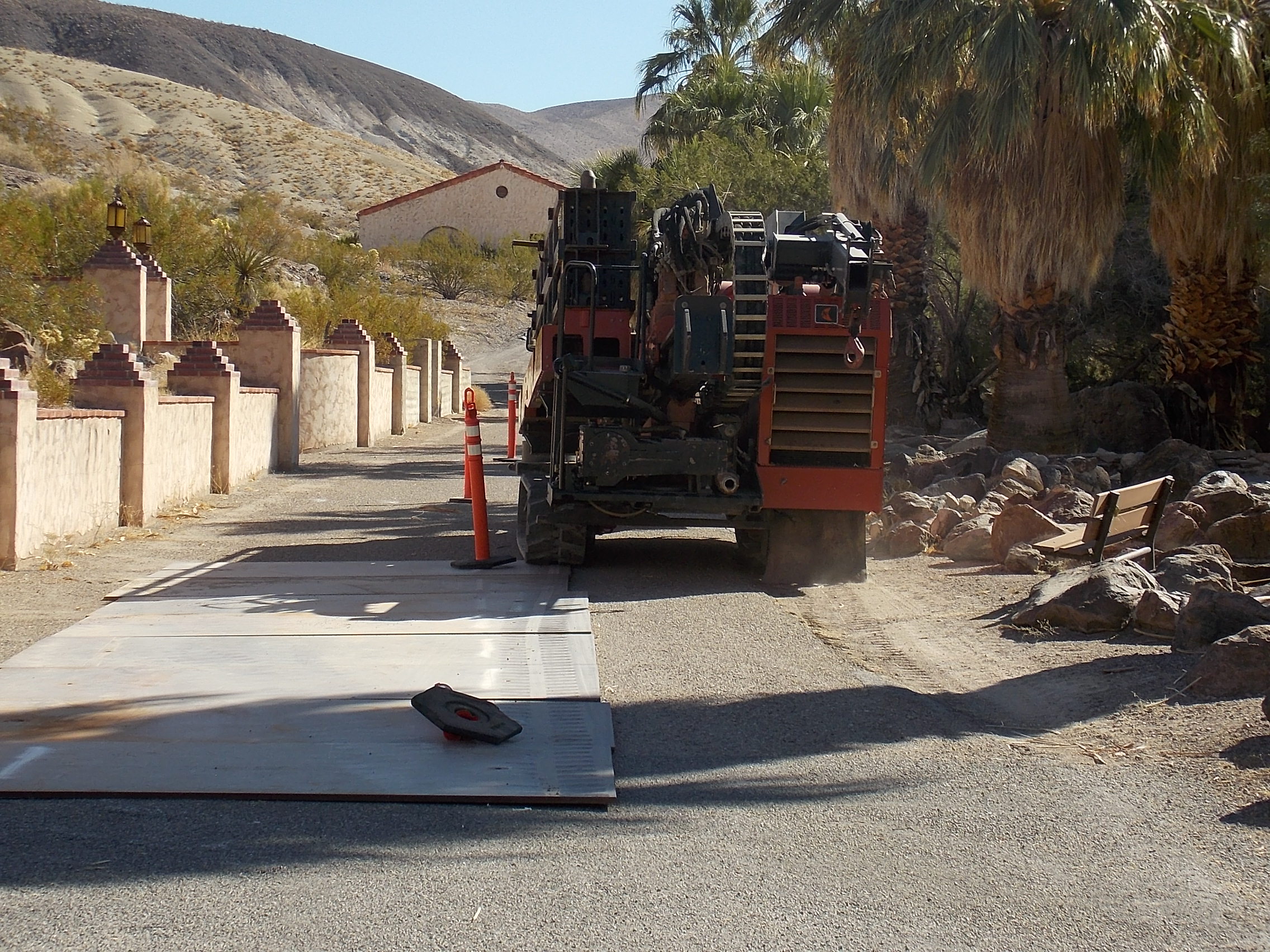 The back of an orange truck is seen squeezed between rocks on the right and orange traffic markers on the left.