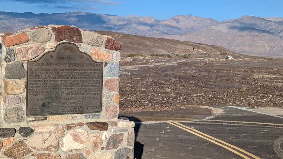 Large stone structure with metal panel in foreground with road covered in debris in the background.