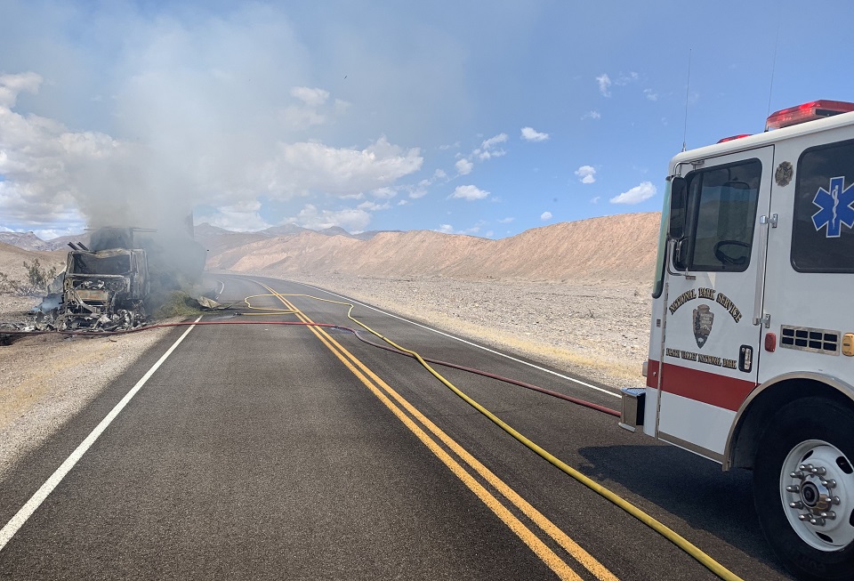 A NPS fire truck is seen in the right side of the image. The burning truck is seen in the distance.