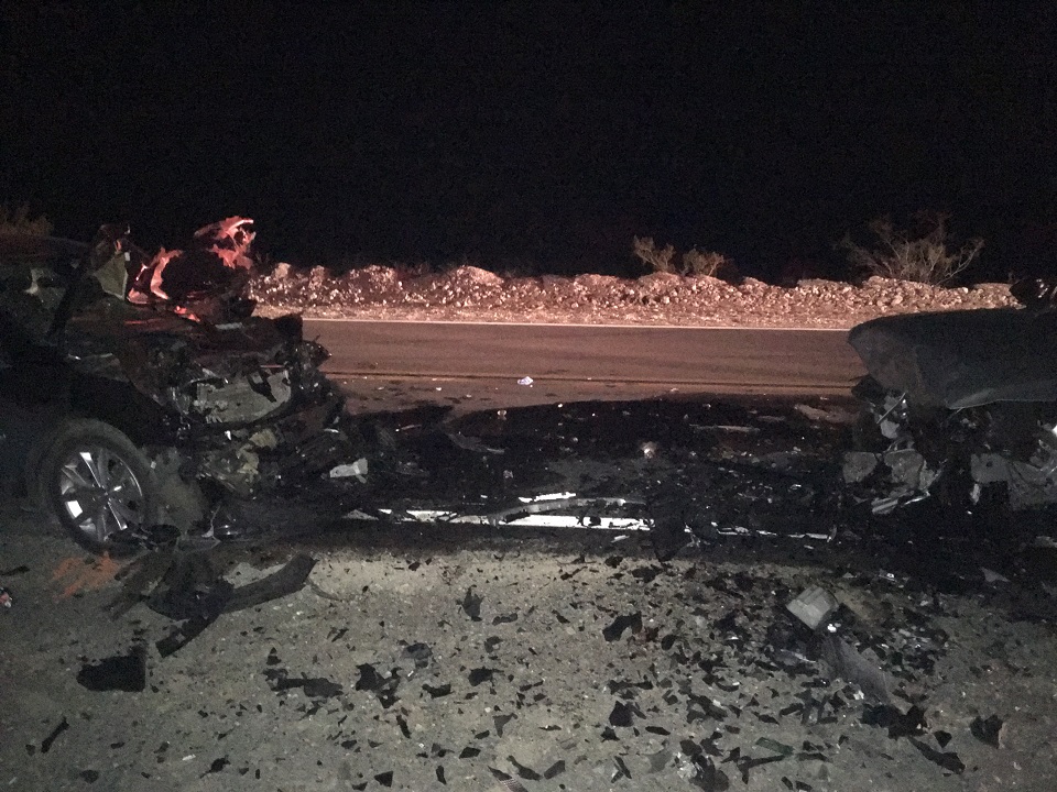 Photograph taken at night shows just the smashed front ends of two cars with debris in between them.