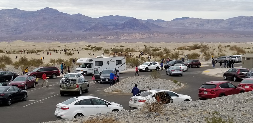 Cars are parked in spaces and along edges of Mesquite Flat Sand Dunes Parking lot on December 23.