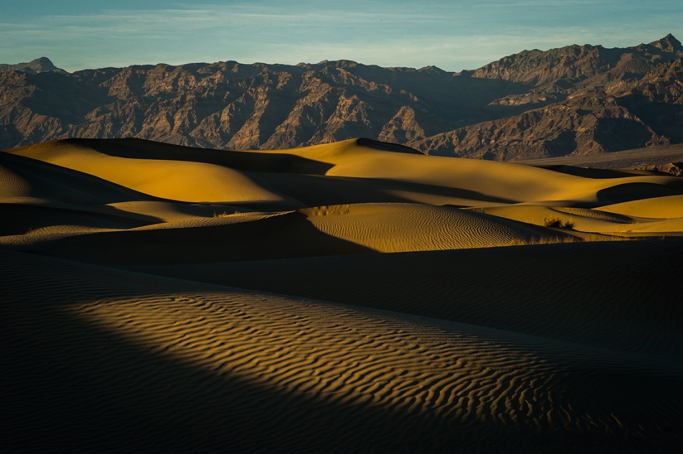 Sand dunes in the foreground and mountains in the background.
